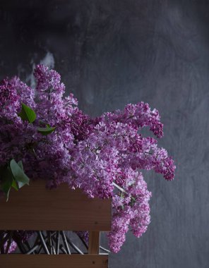 koyu ahşap bir arka plan üzerinde bir sepet içinde leylak buket