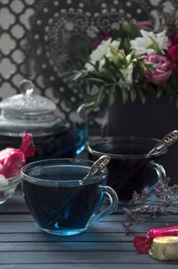 Cam bardak ve çaydanlık Tay mavi çay. Çiçekler ve şekerler.