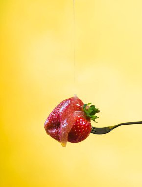 Taze bal veya şeker şurubu sarı bir arka plan üzerinde taze çilek