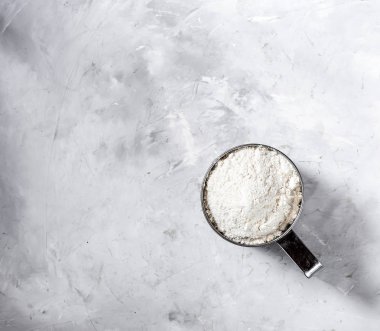 Buğday unu ile metal kupa elek. Gri bir arka plan üzerinde. Yukarıdan görüntüle