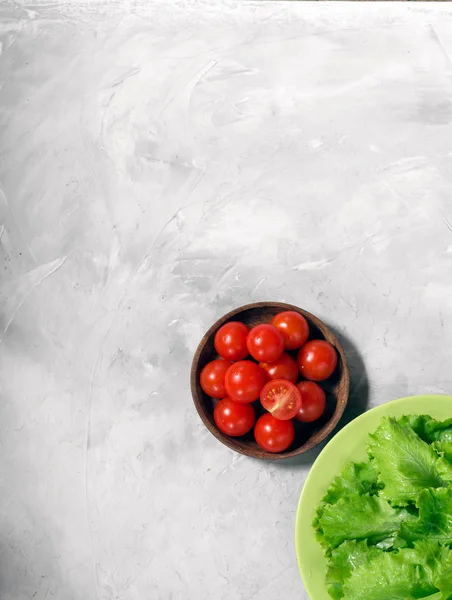 Los tomates cherry y la lechuga se encuentran sobre un fondo gris de hormigón. vista desde arriba. espacio para texto — Foto de Stock