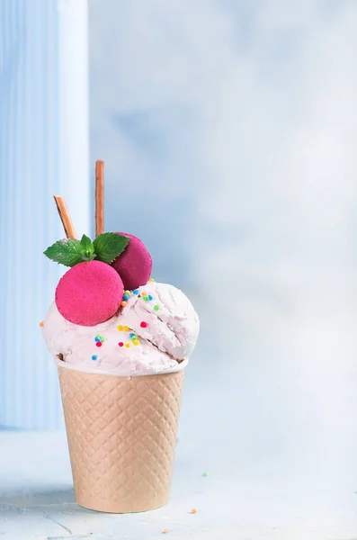 Vanilla ice cream in a paper cup on a blue, turquoise and purple background. With sweets and decorative sweet decorations. Side view. — Stock Photo, Image