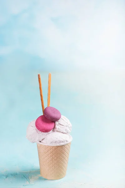 Vanilla ice cream in a paper cup on a blue, turquoise and purple background. With sweets and decorative sweet decorations. Side view. — Stock Photo, Image