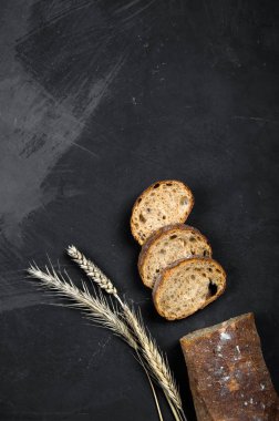 Taze pişmiş çavdar ekmeği koyu bir arka plan üzerinde yatıyor. Yukarıdan görüntüle