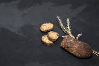 Taze pişmiş çavdar ekmeği koyu bir arka plan üzerinde yatıyor. Yukarıdan görüntüle