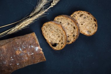 Çavdar unundan yapılmış bir somun taze ekmek. Ekmek dilimler halinde kesilmiş. Ekmek mavi bir arka plan üzerinde yatıyor