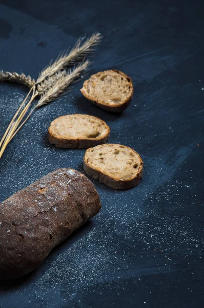 Una pagnotta di pane fresco a base di farina di segale. Pane tagliato a fette. Il pane giace su uno sfondo blu — Foto Stock