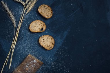 Çavdar unundan yapılmış bir somun taze ekmek. Ekmek dilimler halinde kesilmiş. Ekmek mavi bir arka plan üzerinde yatıyor