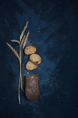 Çavdar unundan yapılmış bir somun taze ekmek. Ekmek dilimler halinde kesilmiş. Ekmek mavi bir arka plan üzerinde yatıyor