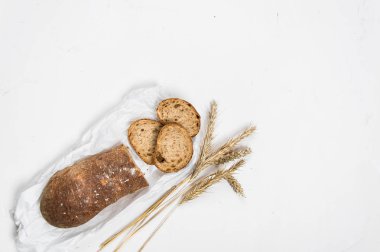çavdar unundan yapılmış koyu ekmek bir somun dilimler halinde kesilmiş beyaz bir arka plan üzerinde yatıyor.