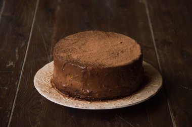 Tahta bir masada kremalı çikolatalı pasta. Renkli kadehler,