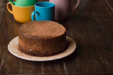 Tahta bir masada kremalı çikolatalı pasta. Renkli kadehler,