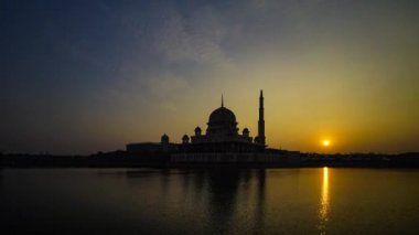Putra Camii 'nde, Putrajaya, Malezya' daki suda yansıyan bir gölün yanında güzel ve dramatik bir gündoğumu hızlandırılmış zaman..