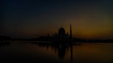 Putra Camii 'nde, Putrajaya, Malezya' daki suda yansıyan bir gölün yanında güzel ve dramatik bir gündoğumu hızlandırılmış zaman..