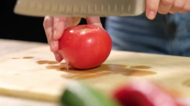 Genç bir kadın olgun bir domates keser. Yakın çekim