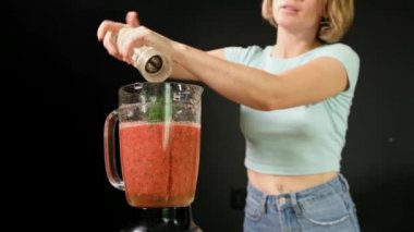 Genç bir kadın çiğ Gazpacho pişiriyor. O bir blender baharat ekler
