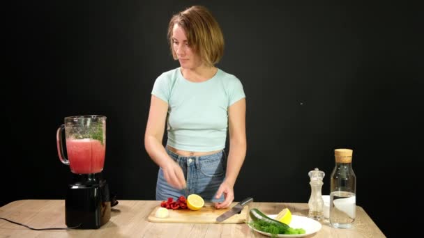 Una giovane donna sta cucinando gazpacho crudo. Mettere le verdure in un frullatore . Clip Video