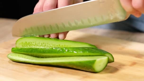 Mujer joven cortando pepino con un cuchillo grande . — Vídeo de stock