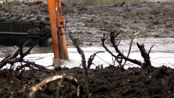 Die breite Schaufel des Baggers gräbt das Erdreich vom Grund des Flusses. Reinigung und Vertiefung des Kanals. — Stockvideo