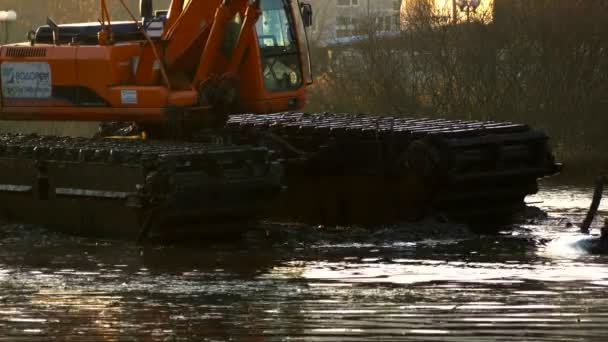 Graafmachines reinigt en verdiept de rivierbedding bij zonsondergang. — Stockvideo