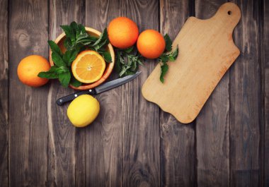 Meyve bir ahşap arka plan üzerine dilimlenmiş. Portakal, limon, nane ve limon balm ahşap arka plan üzerinde. Üstten görünüm. Doğru beslenme bir kavramdır. serinletici bir içki ile meyve.