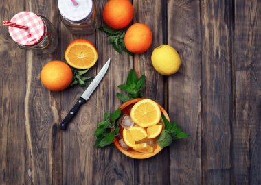 Meyve bir ahşap arka plan üzerine dilimlenmiş. Portakal, limon, nane ve limon balm ahşap arka plan üzerinde. Üstten görünüm. Doğru beslenme bir kavramdır. serinletici bir içki ile meyve.