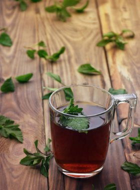 Çay. Nane çayı. Bitkisel çay. Nane yaprağı. Nane yaprakları. Bir cam fincan nane çayına bırakır. otlar çay ve nane yaprakları eski ahşap arka plan üzerinde. Seçici odak.
