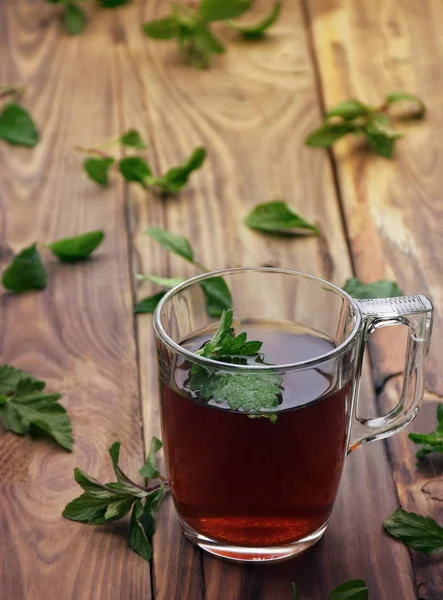 Çay. Nane çayı. Bitkisel çay. Nane yaprağı. Nane yaprakları. Bir cam fincan nane çayına bırakır. otlar çay ve nane yaprakları eski ahşap arka plan üzerinde. Seçici odak.