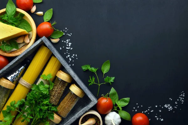 Spaghetti with tomato and basil  on wooden board and ingredients for cooking pasta over dark  background, top view. Food background. Flat-lay.  pasta ingredients : Pasta, olive oil, basil, mushrooms, tomato, garlic, fresh herbs and spices.