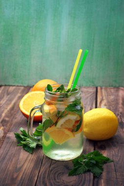 Limon ve nane ahşap bir masa üzerinde su şişesi. su ile limon ve nane, limon balm, ahşap arka plan üzerinde bırakır. Maden suyu. Yaz içeceği. Detoks.