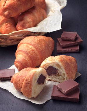 Kruvasan. Ev yapımı taze altın kruvasanlar koyu ahşap arka plan. Kruvasan çikolata dolgulu.