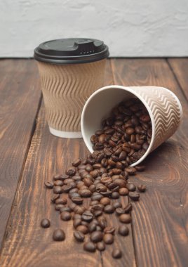 Tahta bir masada bir fincan sıcak kahve ve kahve çekirdeği. Büyüleyici aroma ve zengin lezzet, kahvaltı için ideal.