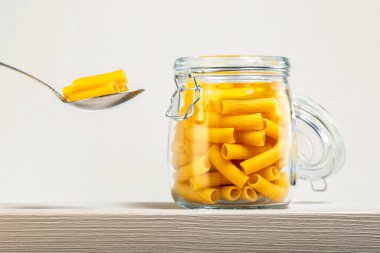 Ahşap bir rafta kavanozda makarna.