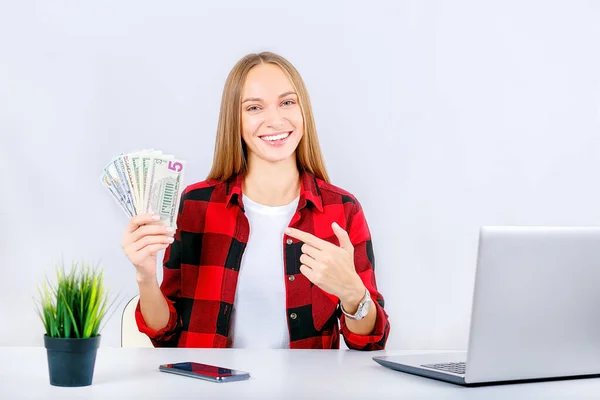 Portre genç, mutlu, başarılı, genç bir iş kadını elinde para banknotları tutuyor. Finansal ödül, geri ödeme..