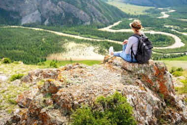 Sırt çantalı kadın dağın tepesinden manzaranın tadını çıkarıyor..