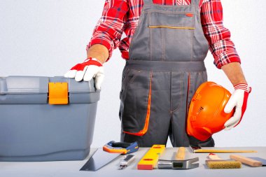 Masasında alet çantası ve aletleri olan gri üniformalı bir işçi. Ev onarımı kavramı. 