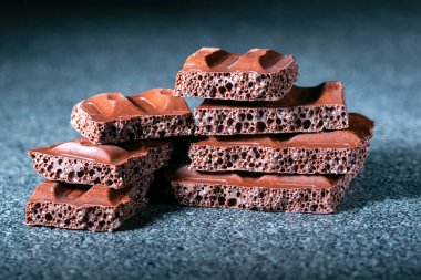 Koyu renk parçalar, gri yüzeyde sütlü çikolata..