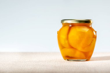 Masanın üzerinde cam kavanozda konserve şeftali. Boşluğu kopyala.