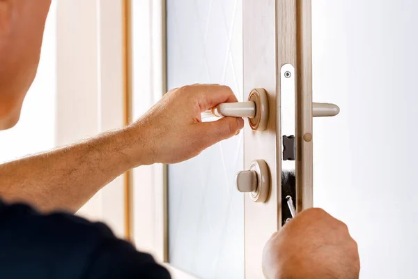 Man repairing the lock of door. Technician fixing lock in door with screwdriver.