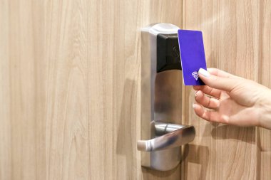 Kapıları kilitleyip açmak için elektronik anahtar sistemi. Kapı kontrolü için kadın el kartı. Kapıyı kilitleyip açmak için anahtar kartı taranıyor..