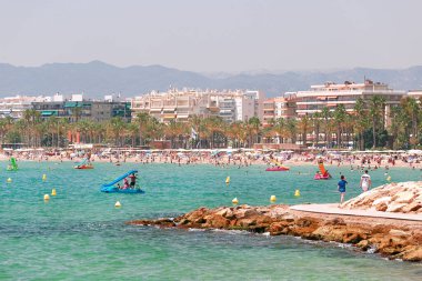Şeffaf ve turkuaz deniz, Salou, İspanya 'da turistlerle dolu plaj. 
