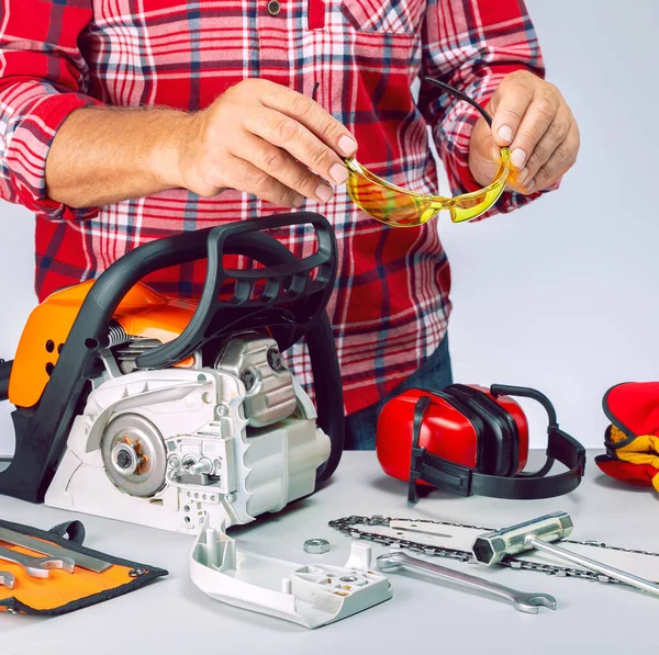Tamirci tamirhanedeki elektrikli testereyi tamir ediyor. Teçhizatlı ve testereli tamirci..