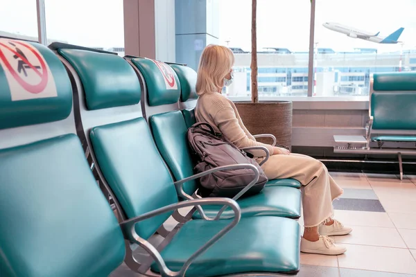 Kobieta Masce Spogląda Przez Okno Siedzi Krześle Towarzyskim Lotnisku Podróże — Zdjęcie stockowe