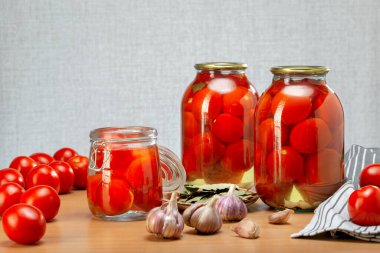 Ev yapımı domates turşulu cam kavanozlar, masada taze domates ile mühürlenmiş.. 