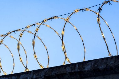 duvarda geometrik bir desen oluşturan mavi gökyüzüne karşı dikenli çit arka plan