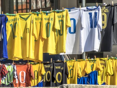 Sao Paulo, Brezilya, 12 Temmuz 2019. Farklı futbol takımlarının t-shirt Charles Miller Meydanı'nda bir sokak satıcısı tarafından, Paulo Machado de Carvalho Belediye Stadyumu önünde, Pacaembu Stadyumu olarak bilinen, Sao Paulo batısında satılmaktadır