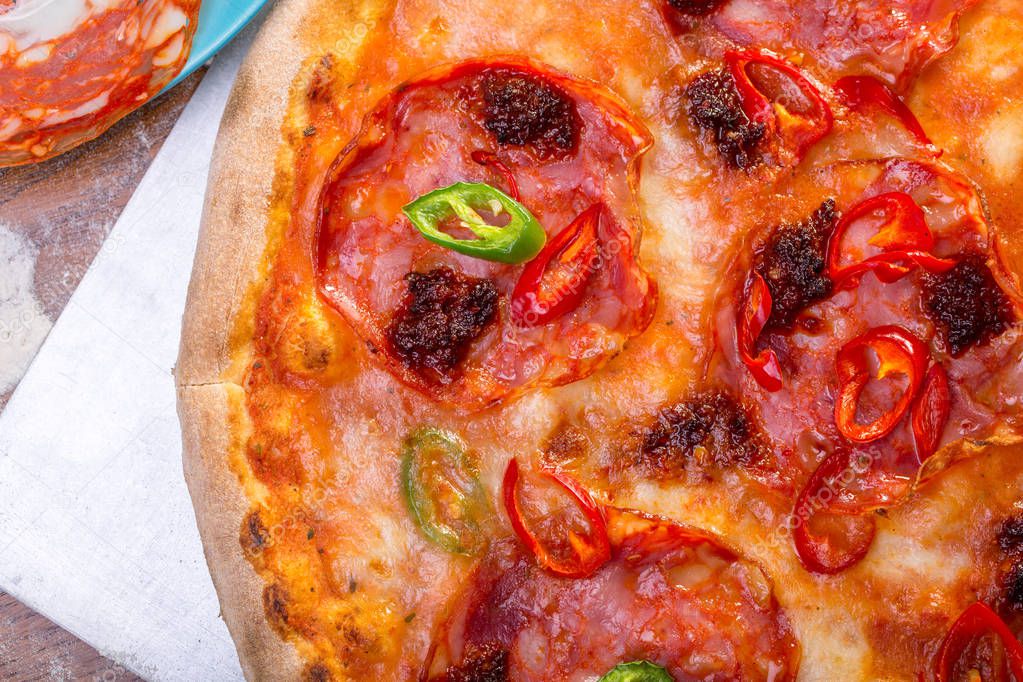 close up of tasty spicy pizza with salami, mozzarella and peppers