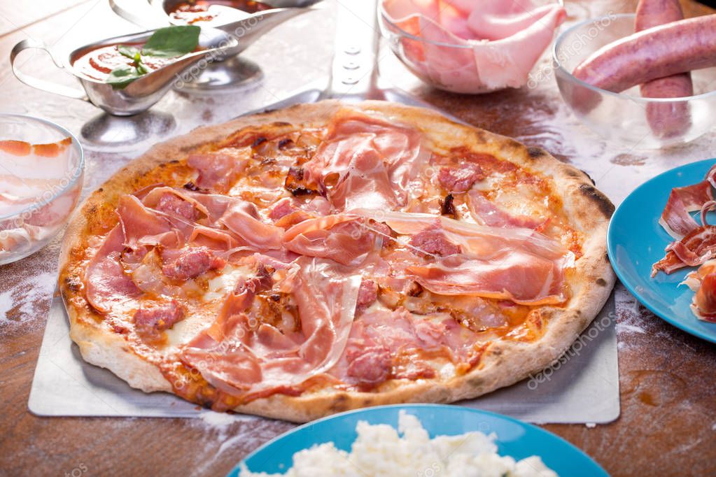 close up of tasty pizza with sausage, ham and smoked meat