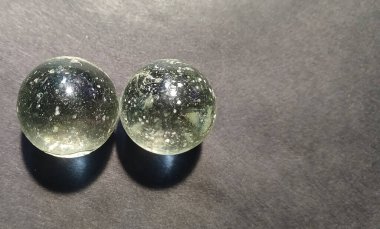 Parlak bir efekt ve yumuşak bir gölge yaratmak için ışık tarafından aydınlatılan, koyu dokulu bir yüzeye yerleştirilmiş, temiz cam mermerin yakın çekimi..