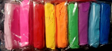 Şeffaf ambalaja sarılı canlı modelleme kil bloklarının yakın plan görüntüsü ve siyah arkaplan üzerinde sıralanması.